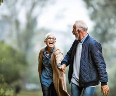 Cheerful senior couple having fun in the park. Focus is on woman. Copy space.